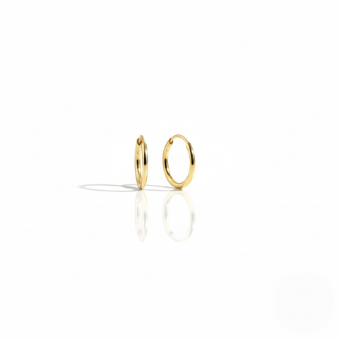 A pair of minimal polished 10K yellow gold Keeper Hoops on a white background, highlighting its seamless design.
